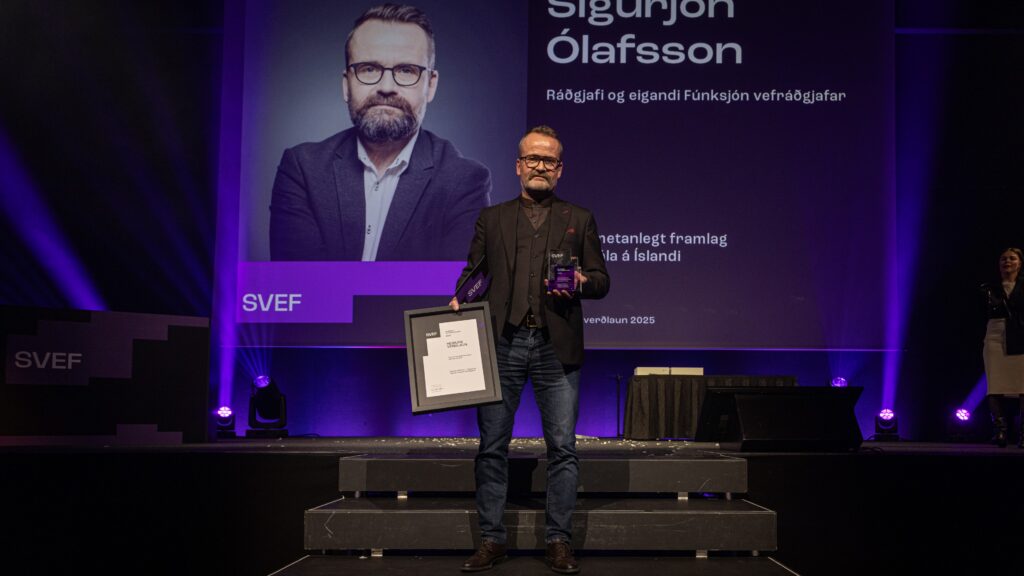 Sigurjón Ólafsson hold a trophy for "person of honor" on stage at the 2025 Iceland Web Awards (Íslensku vefverðlaunin 2025).
